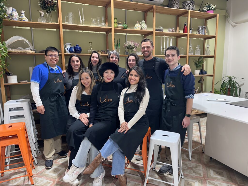 Familia de turistas disfrutando de las clases de cocina en Madrid, aprendiendo a preparar platos típicos con Lóleo.