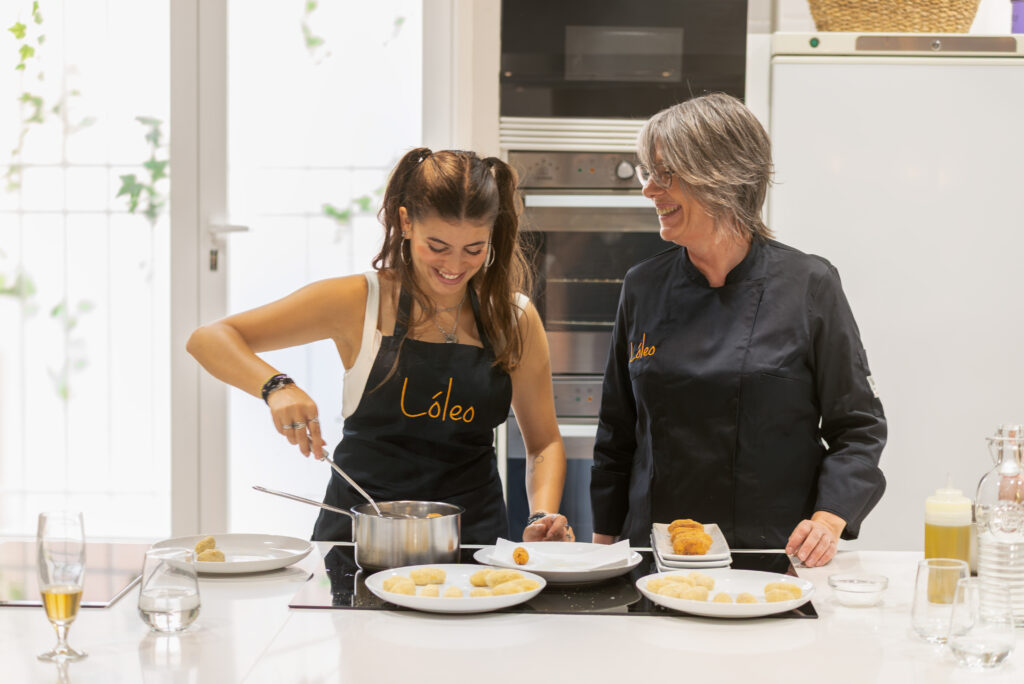 Lola con una alumna riendo mientras que cocinan